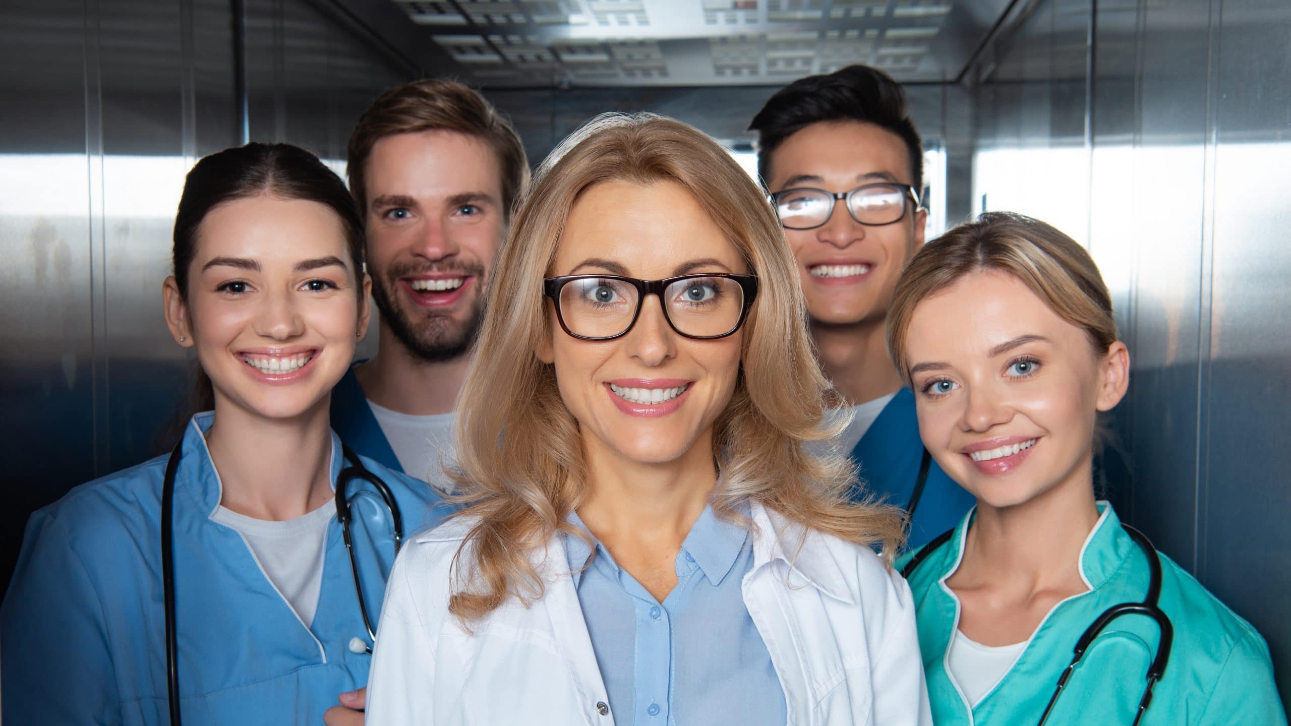 smiling teacher and multicultural students standing in elevator at medical university