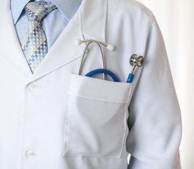 Doctor in medical gown with blue stethoscope, close up