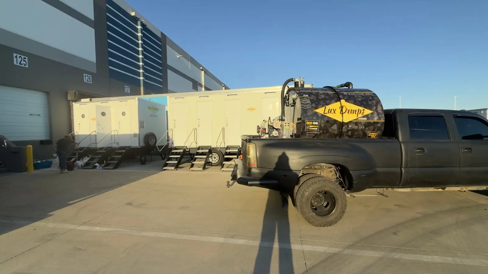 Lux Dumps pump truck servicing luxury restroom trailers at a distribution centre in Southern California