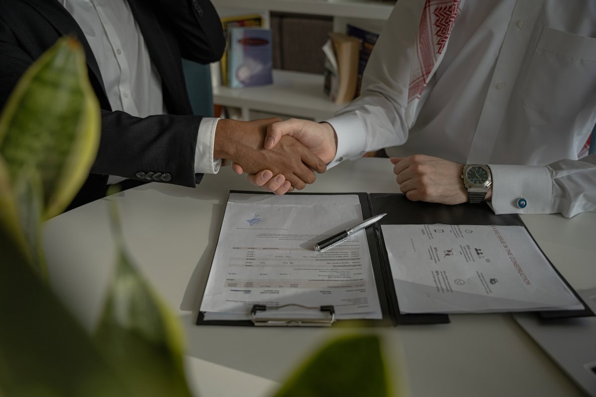 Deux personnes se serrant la main au-dessus d'un document, symbolisant la renégociation d'un contrat de mutuelle collective d'entreprise