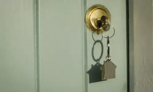 A house front door key with a house shaped key ring