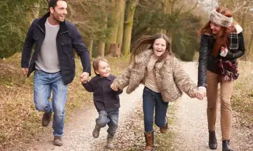 Family Running On Winter Countryside Walk Together