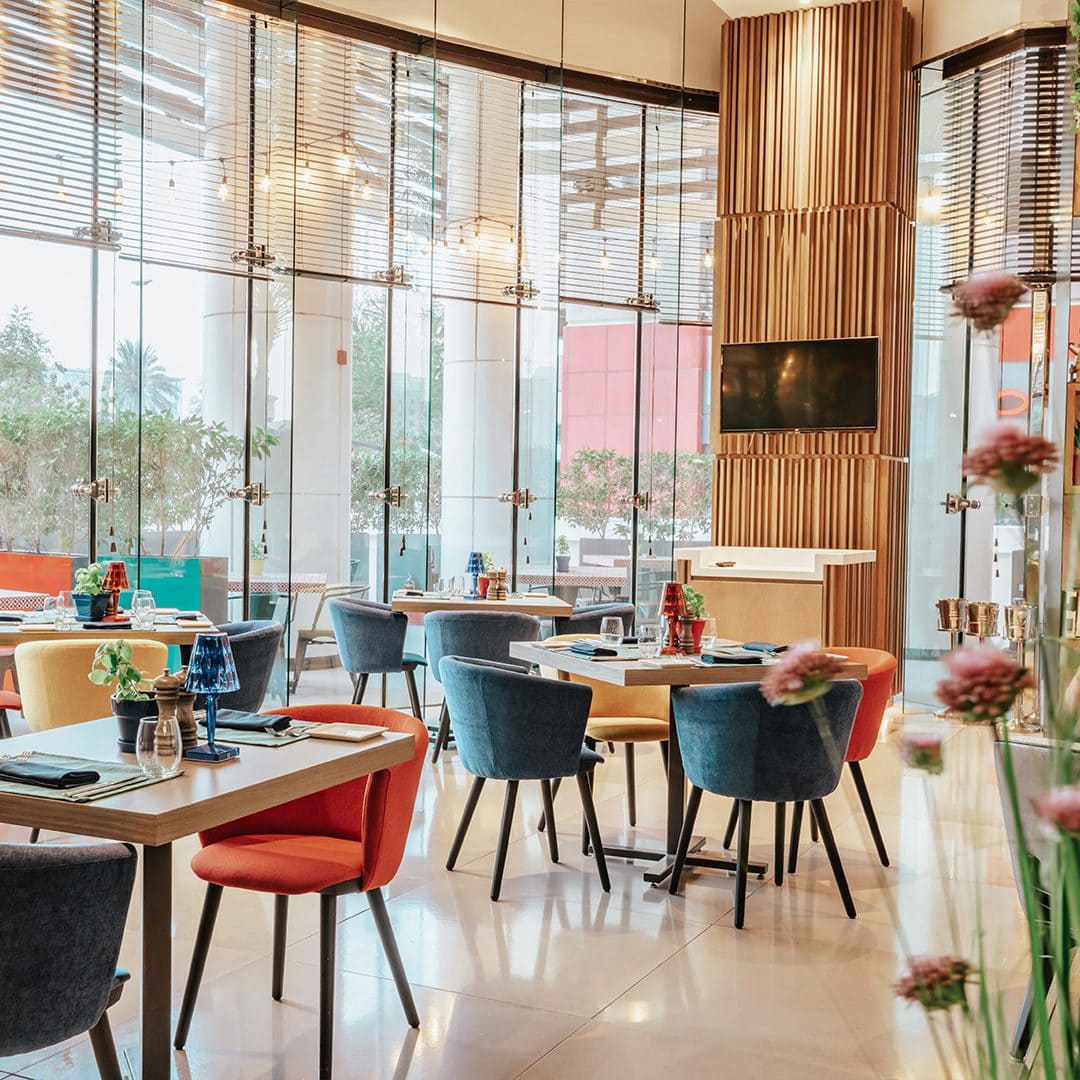 Bright and modern dining area at Coco Lounge, featuring colorful chairs, sleek tables, and natural light through glass walls.