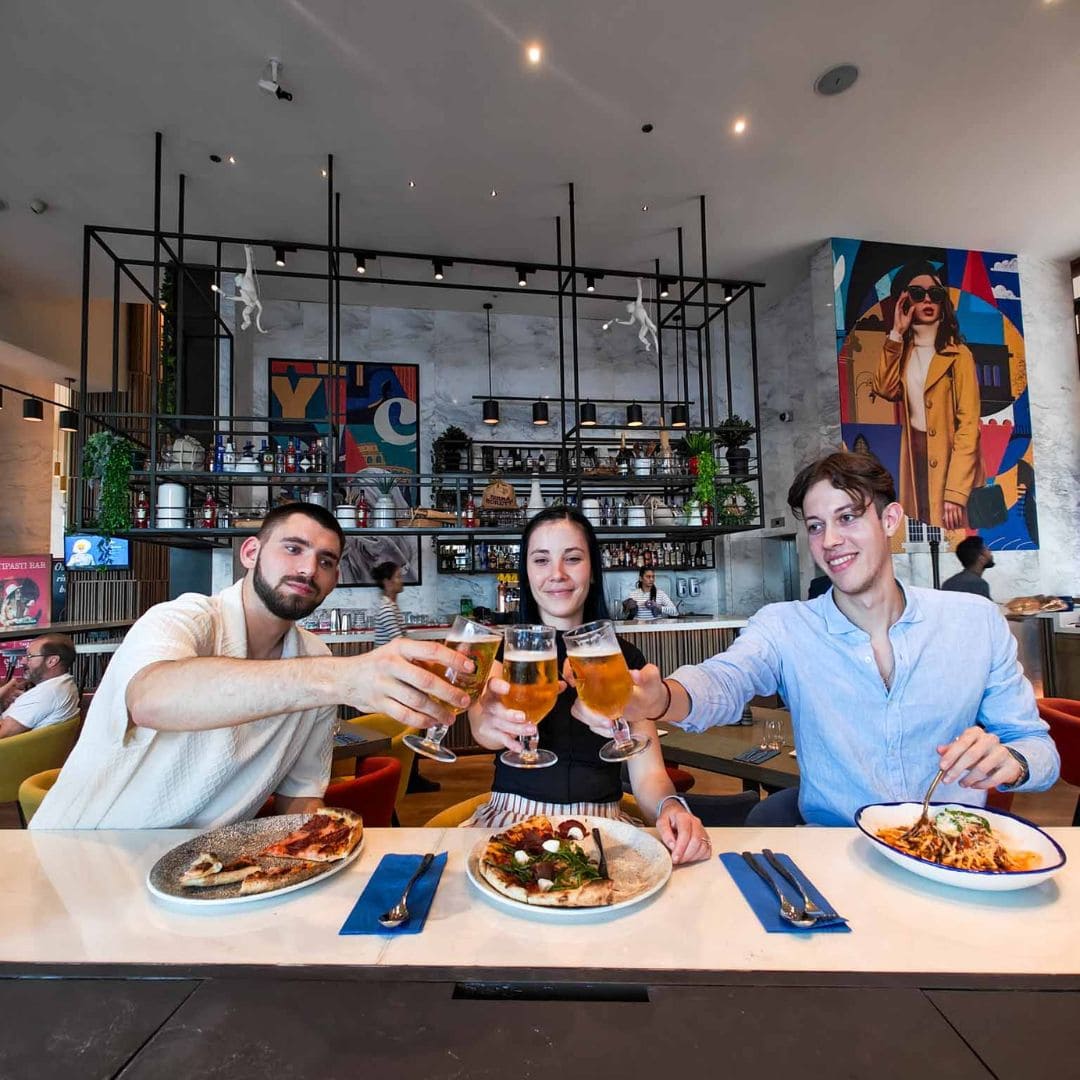 Friends enjoying Italian cuisine and drinks at Ciao Bella, a lively restaurant with vibrant decor and a social atmosphere.
