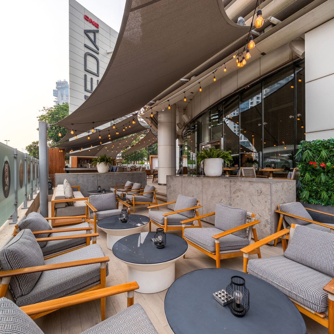 Outdoor seating area at Garden on 8, featuring modern furniture, hanging lights, and vibrant greenery at Media One Hotel.