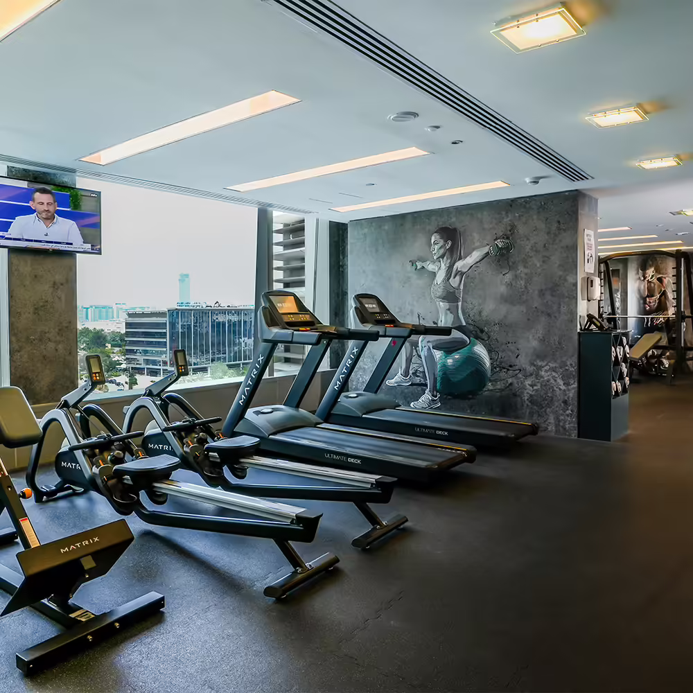 Gym-Internal Media One Hotel gym with rowing machines, treadmills and a window showing the city.