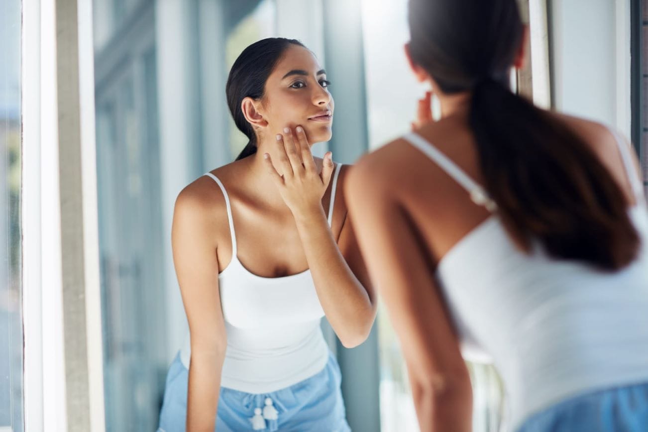 Woman examining her skin in the mirror after Morpheus8 treatment for facial rejuvenation