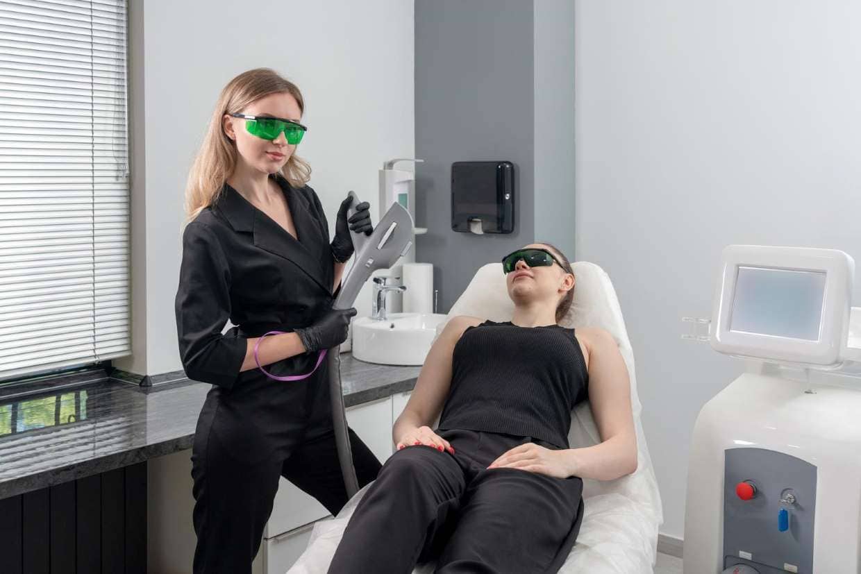 Esthetician preparing a client for laser hair removal treatment at a medical laser spa Toronto clinic, both wearing protective goggles.