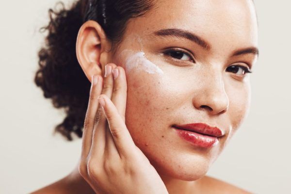 Woman applying acne treatment cream to her face.