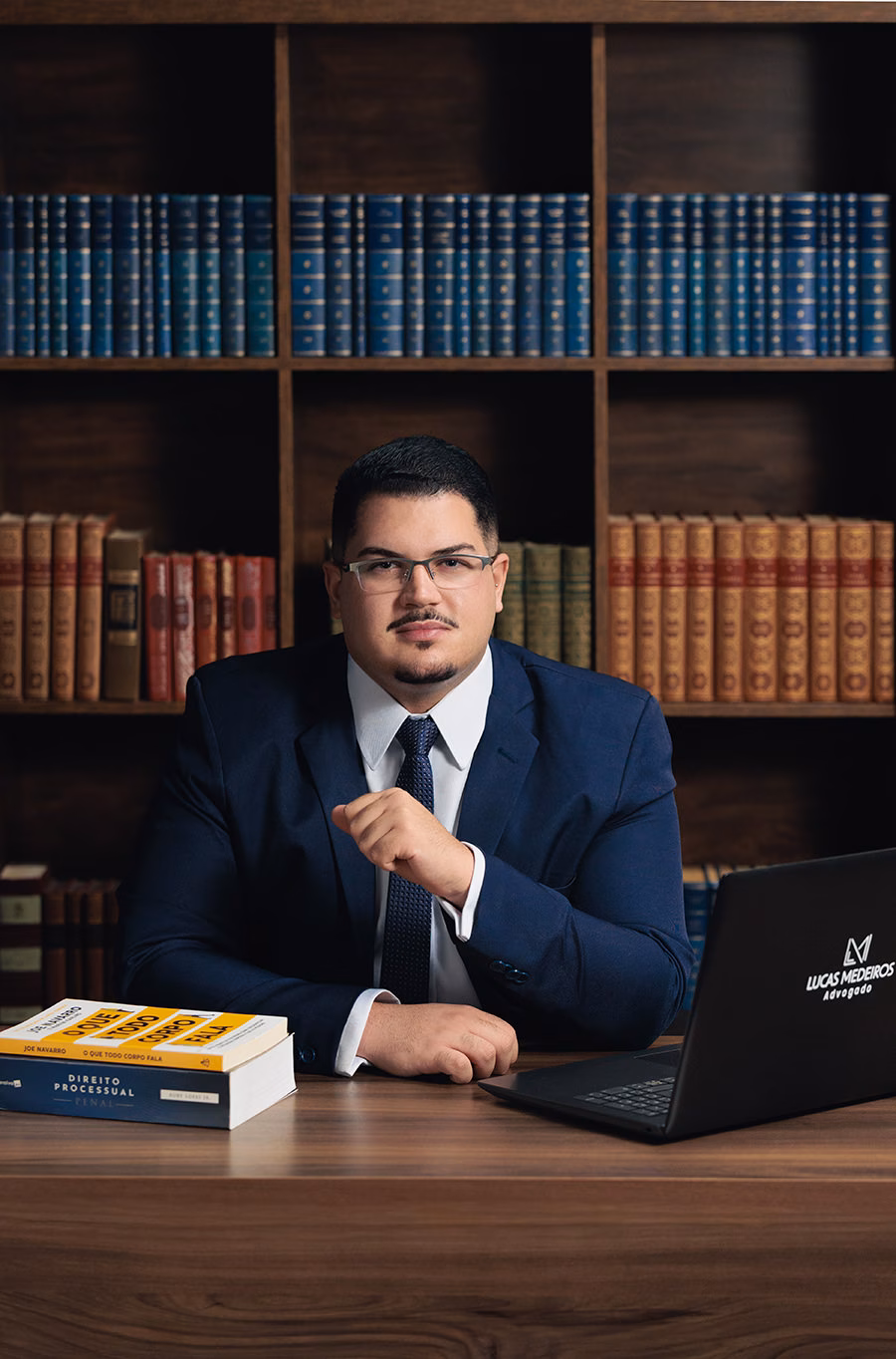 Retrato corporativo de advogado com notebook e estante ao fundo no estúdio em BH