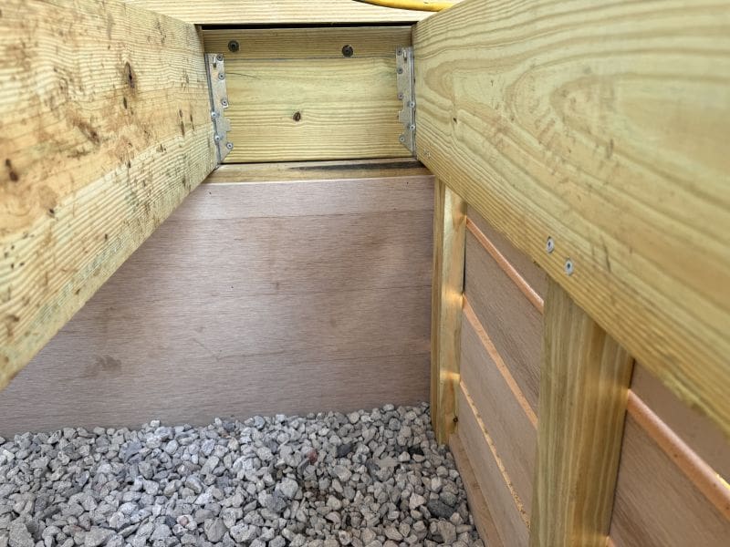 inside deck modern mill joist hangers How Do I Stop Animals From Dying Under My Deck MyFixitUpLife MyFixitUpLife Inside view of a wooden framed structure with metal brackets showing planks and gravel ground beneath MyFixitUpLife