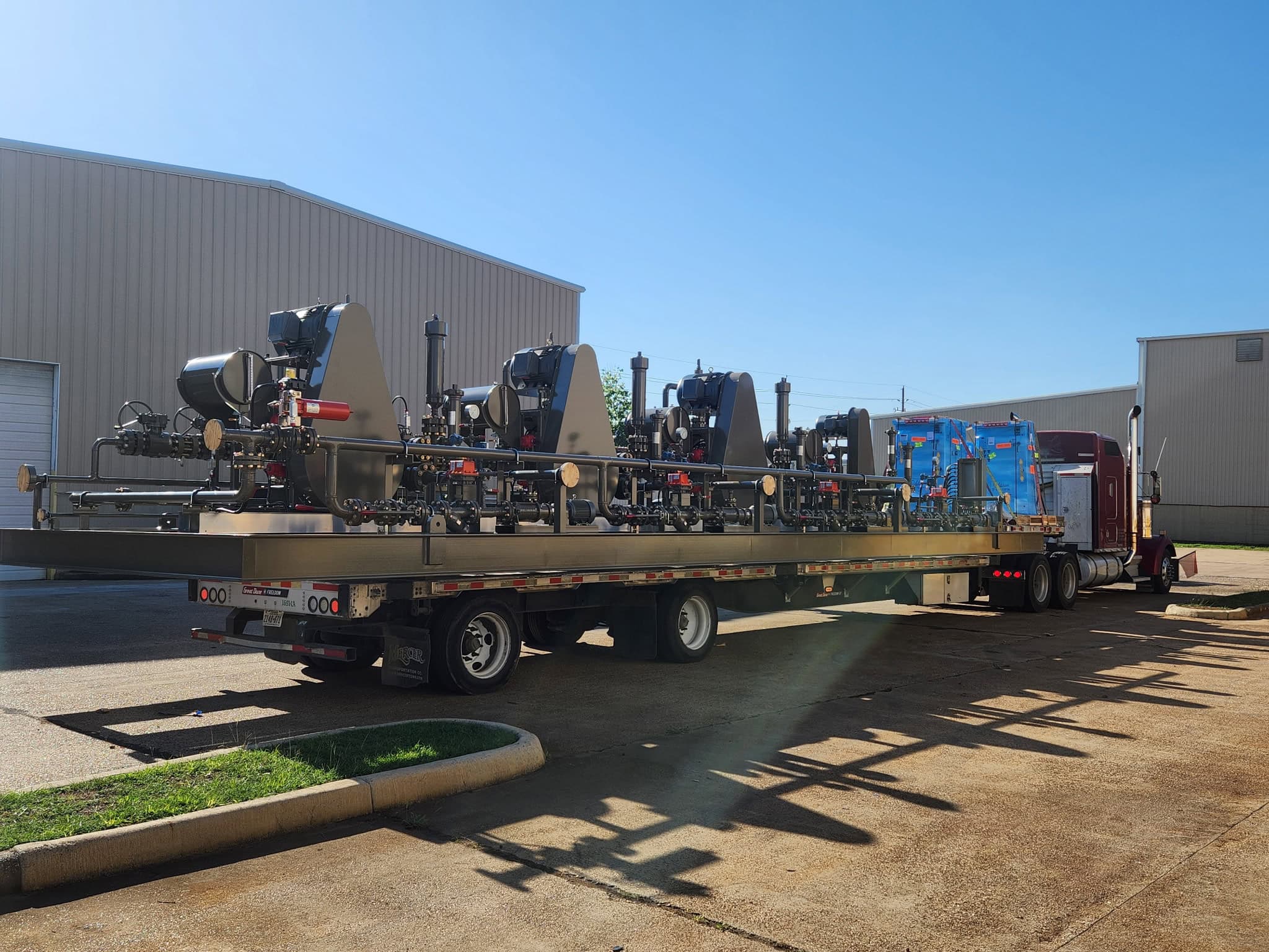 Multi-pump process skid package loaded on a flatbed truck outside the WeldIT shop for delivery to the customer