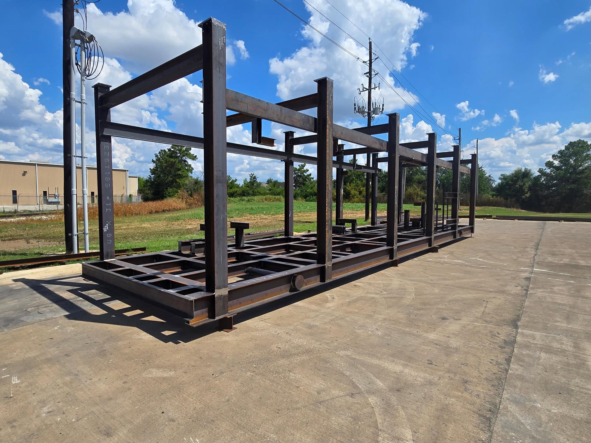 Long welded structural steel equipment skid base with columns and cross members on a concrete yard outside the WeldIT shop