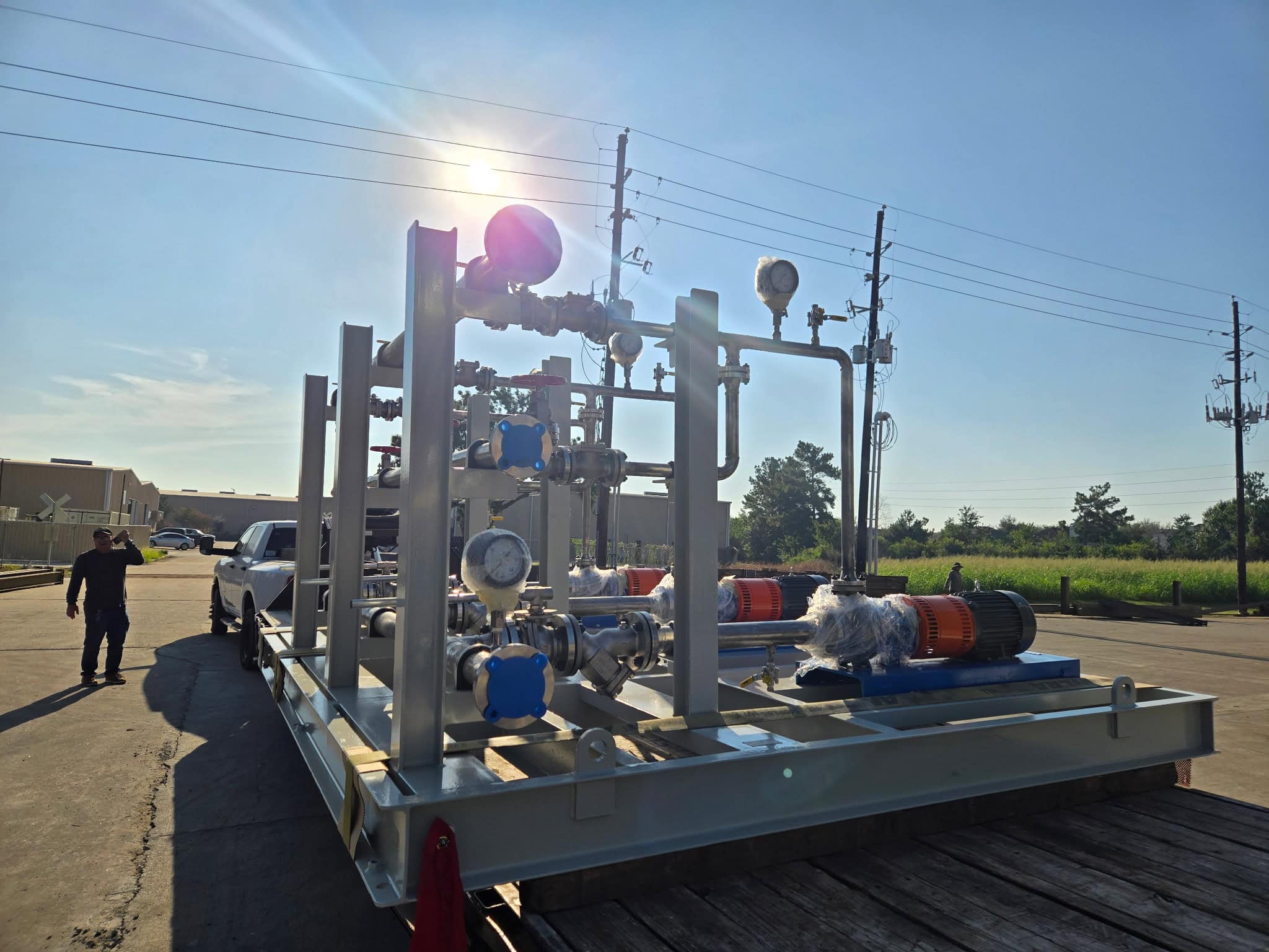 Skid-mounted pump package with stainless steel piping, gauges and valves on a structural steel base staged outside the WeldIT shop