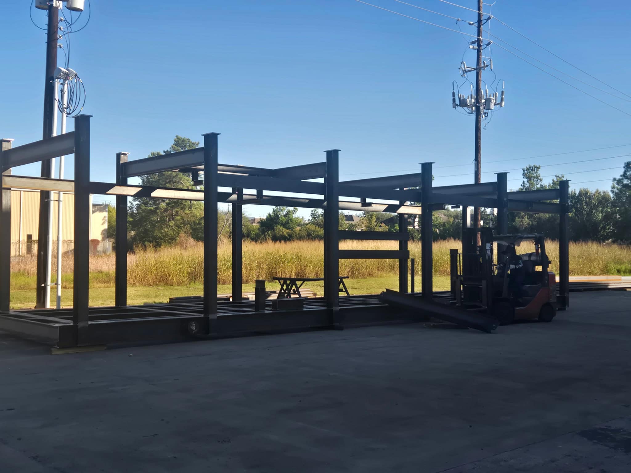 Completed multi-bay structural steel skid structure standing outside the WeldIT shop with a forklift nearby