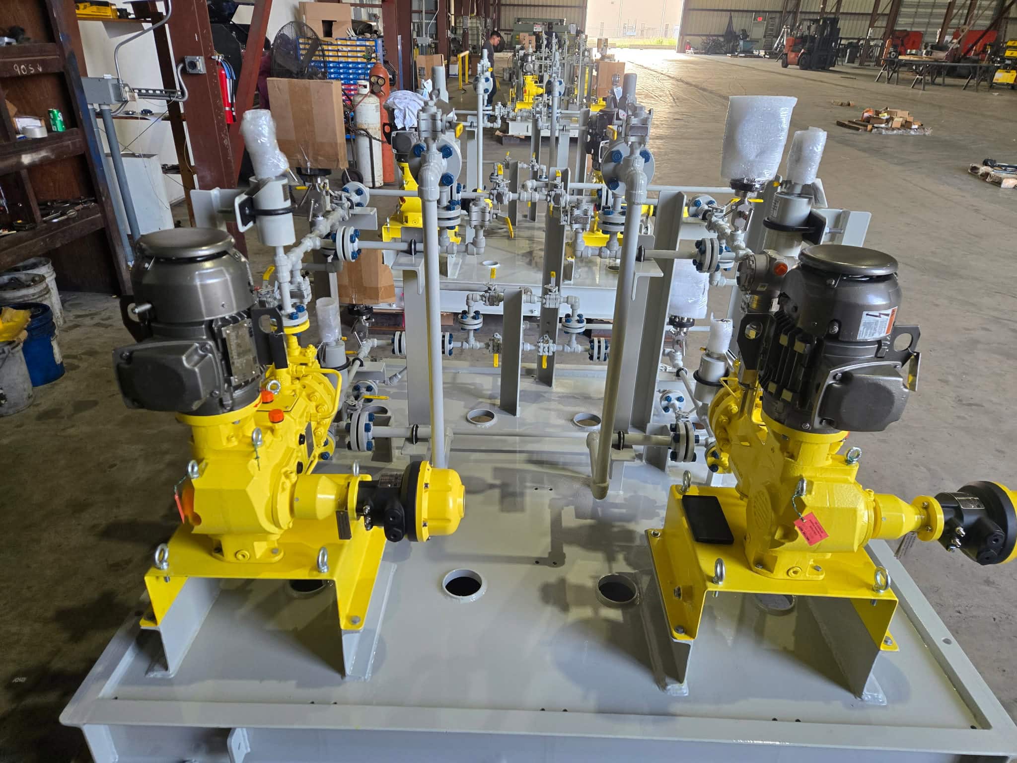 Chemical injection skid package with dual yellow metering pumps, stainless piping and valves on a gray structural steel base, fabricated by WeldIT in Houston, TX