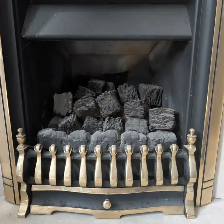 A traditional black and gold inset gas fireplace with a decorative brass front grate and ceramic coal firebed matrix, serviced and safety checked by NB Gas & Plumbing in Glasgow.