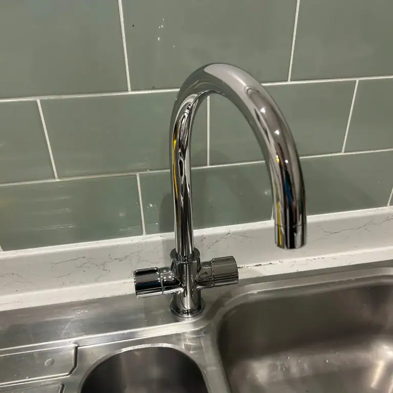 Newly installed modern chrome mixer tap on a stainless steel kitchen sink, completed by a professional plumber in Glasgow.
