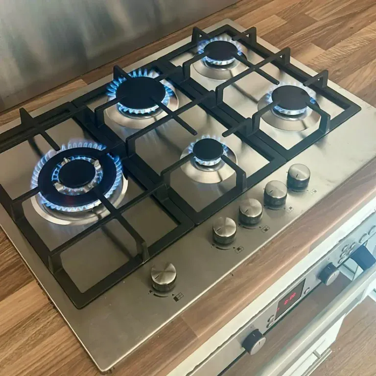 Stainless steel 5-burner gas hob installation in Knightswood, Glasgow, by NB Gas And Plumbing featuring lit blue flames and cast iron pan supports