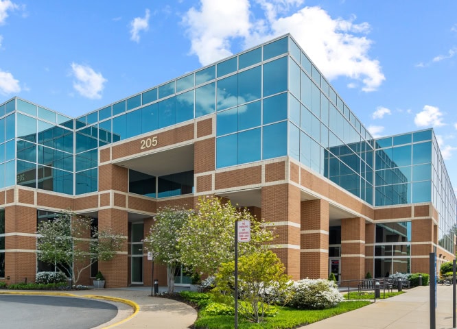 Modern office building with glass exterior and brick accents promoting Office Evolution franchising opportunities.