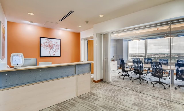 Modern office reception area with a glass-walled conference room, perfect for professional meetings, featuring contemporary decor and a welcoming environment.