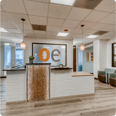 Modern office reception area with Office Evolution branding, featuring a stylish white counter, ambient lighting, and comfortable seating, perfect for franchise clients and business professionals.