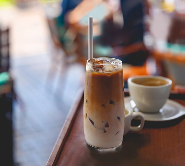 Unrecognizable waitress taking ice coffee with paper straw to a customer, Nikon Z7