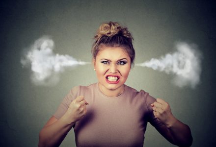 Closeup portrait angry young woman blowing steam coming out of ears, about to have nervous atomic breakdown screaming isolated black background. Negative human emotion face expression feeling attitude