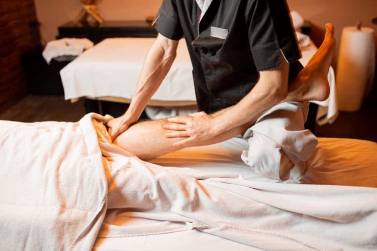Deep tissue massage therapist stretching leg to relieve chronic pain - One Body LDN Deep tissue massage therapist stretching leg to relieve chronic pain Physiotherapy in London