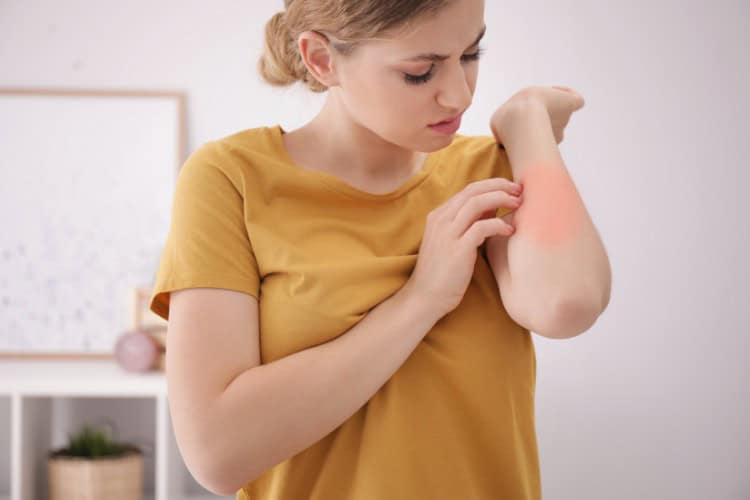 Woman examining inflamed forearm showing signs of elbow pain - One Body LDN Woman examining inflamed forearm showing signs of elbow pain