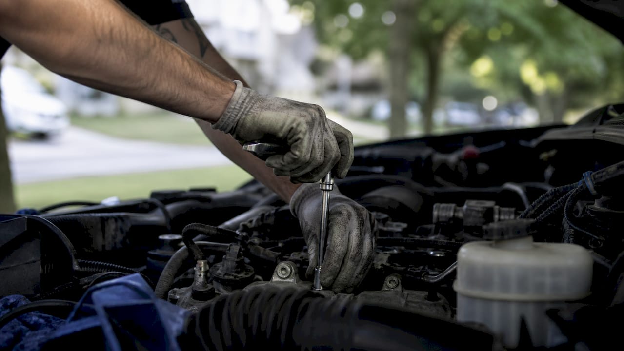Mechanic hands replacing spark plugs outdoors