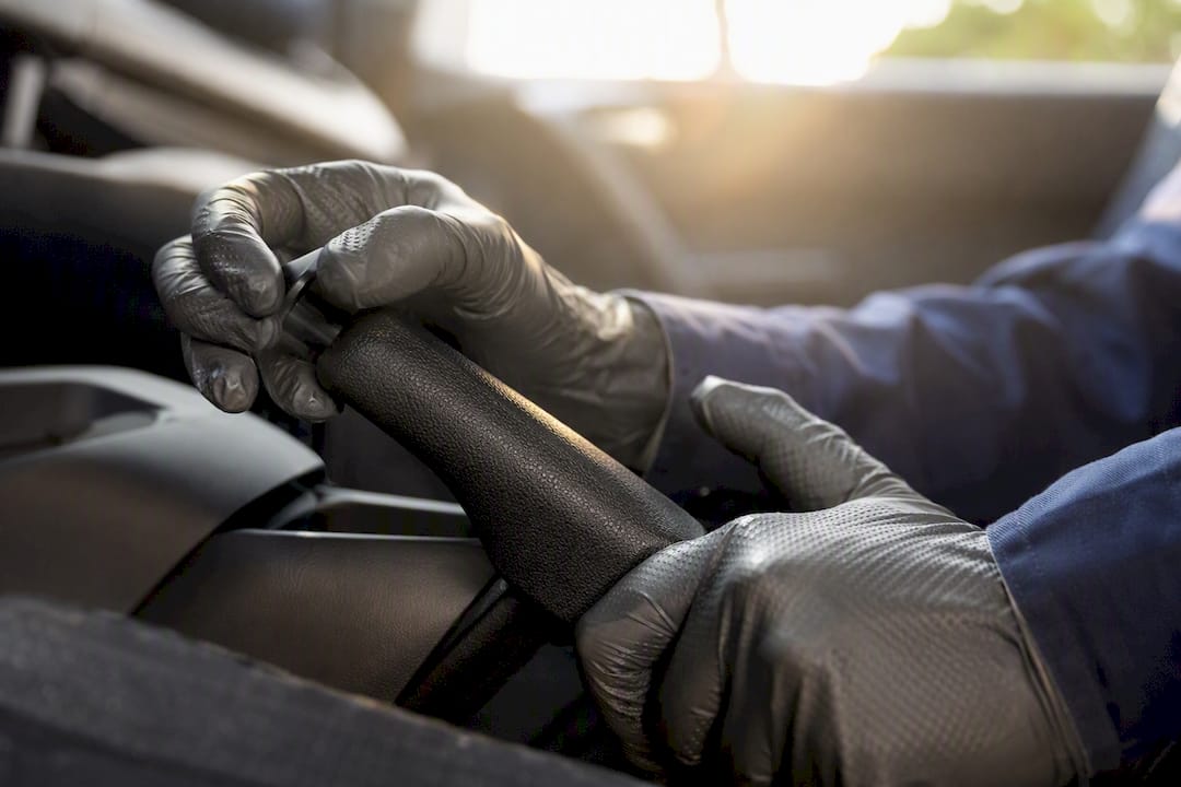 Hands releasing parking brake lever inside car