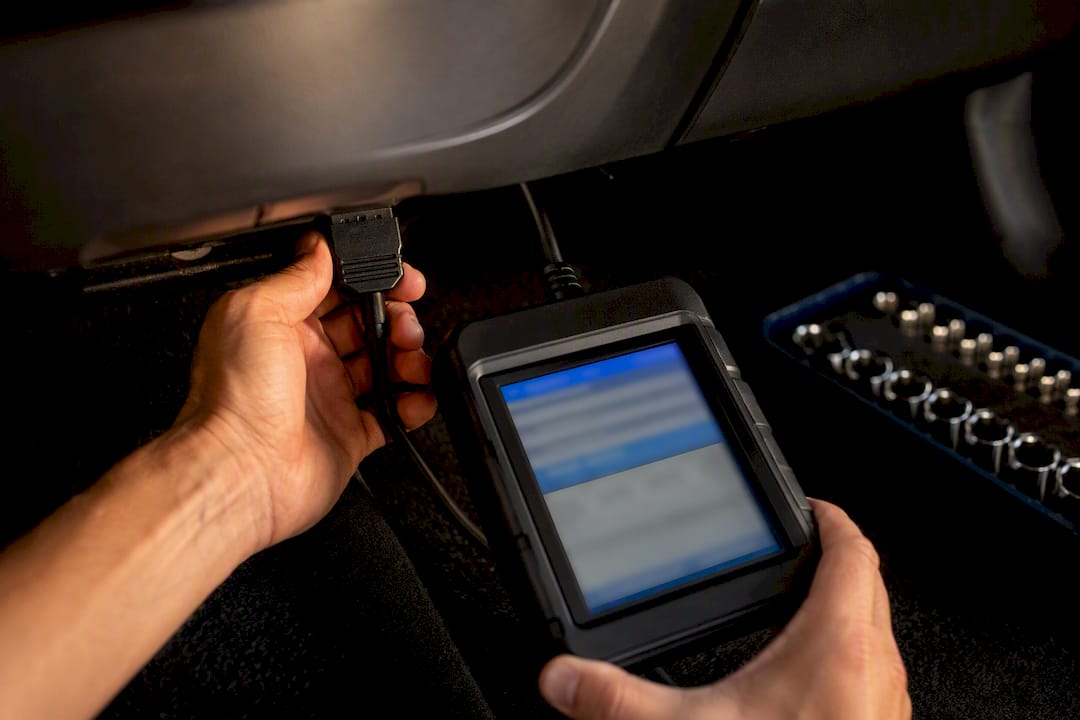 Technician connecting scan tool beneath dashboard