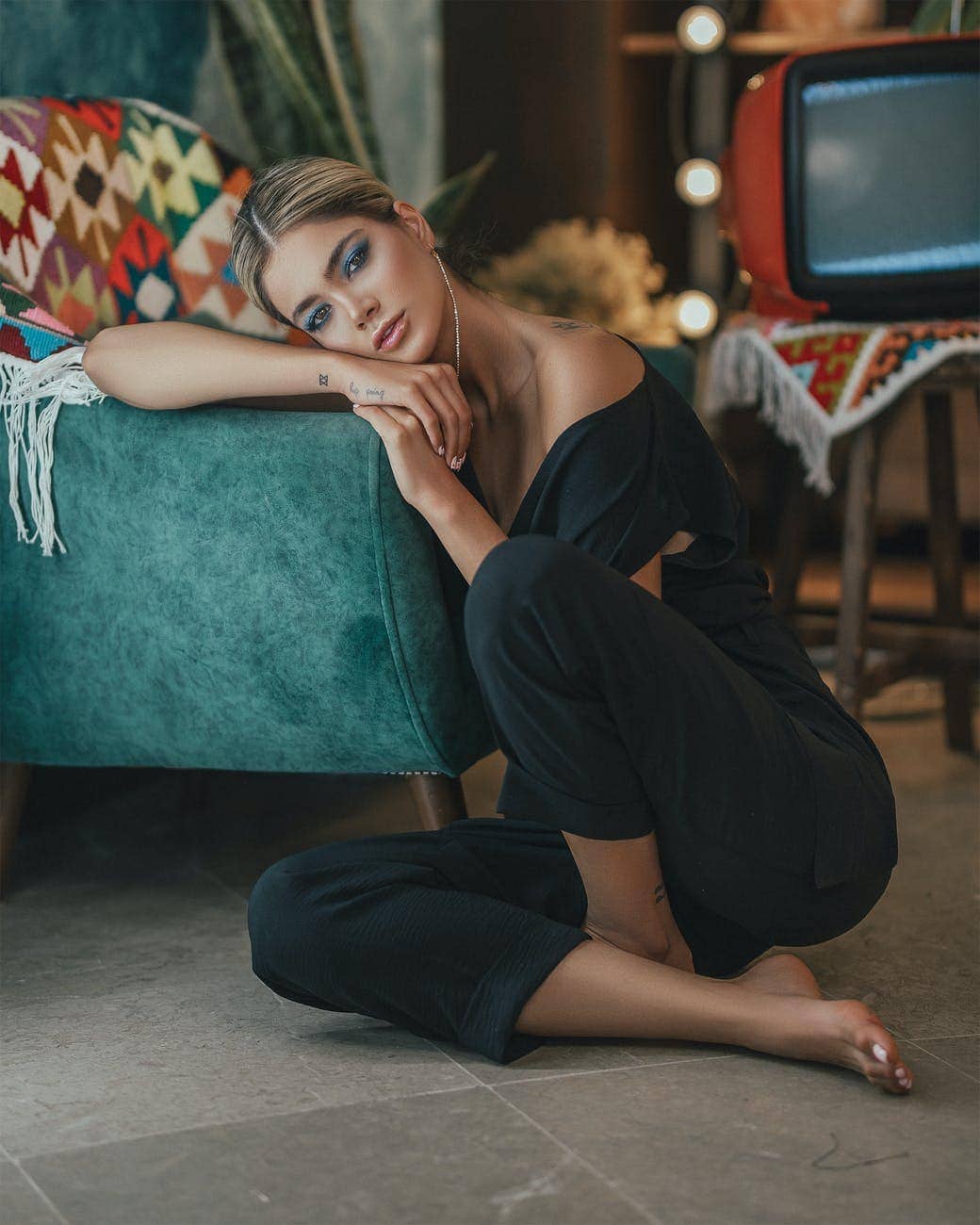 A tired and bored looking woman with a television in the background