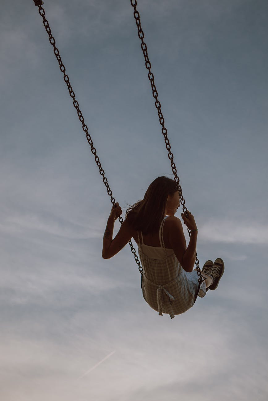 A girl contentedly swings high on a swing