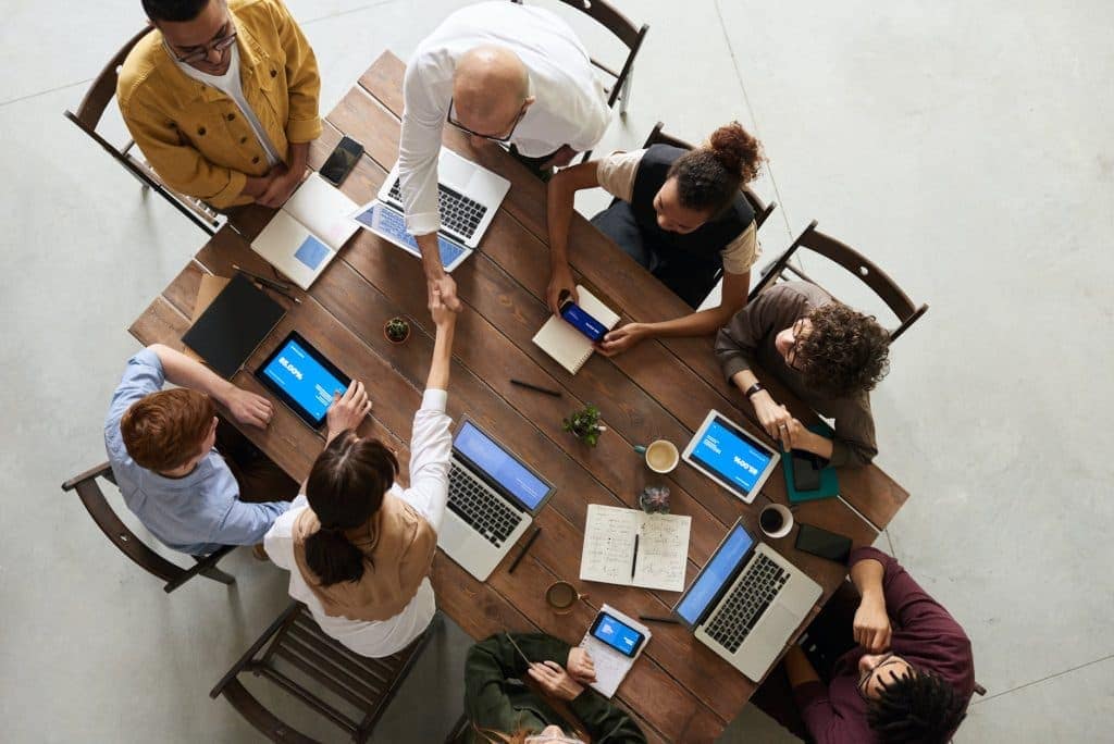 A committee meeting around a table with lots of computers