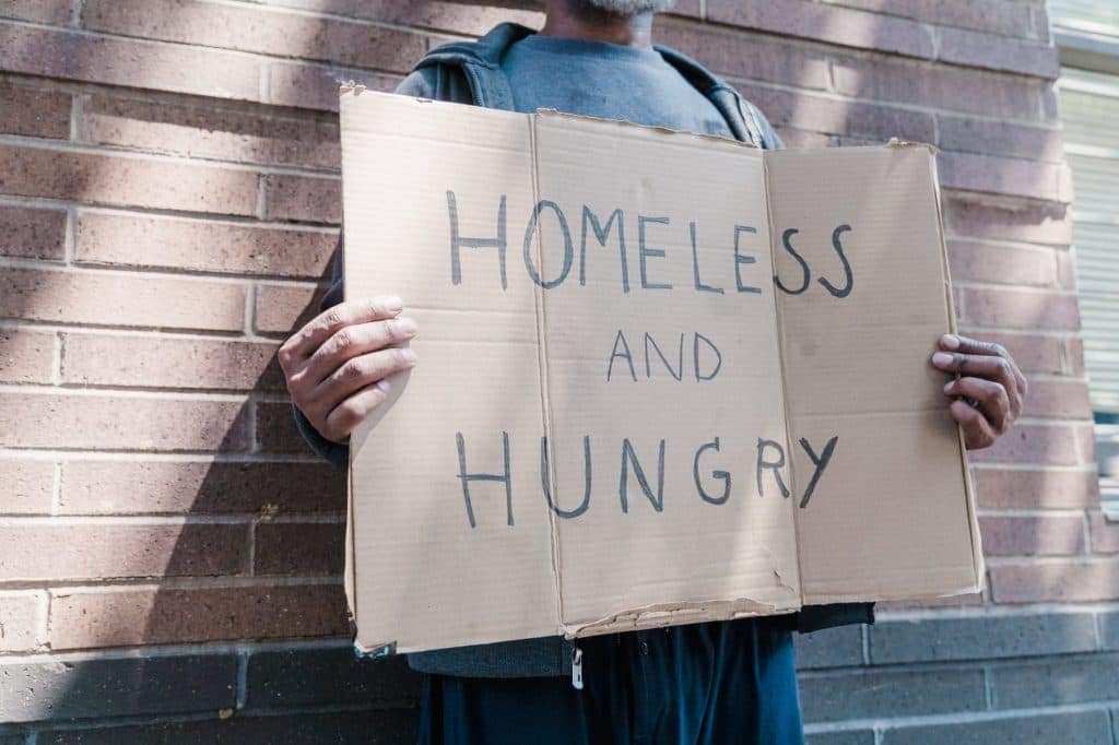 A man carrying a begging sign - Homeless and hungry