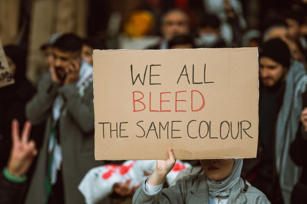 Highlighting discrimination, a person holds a sign that says we all bleed the same colour