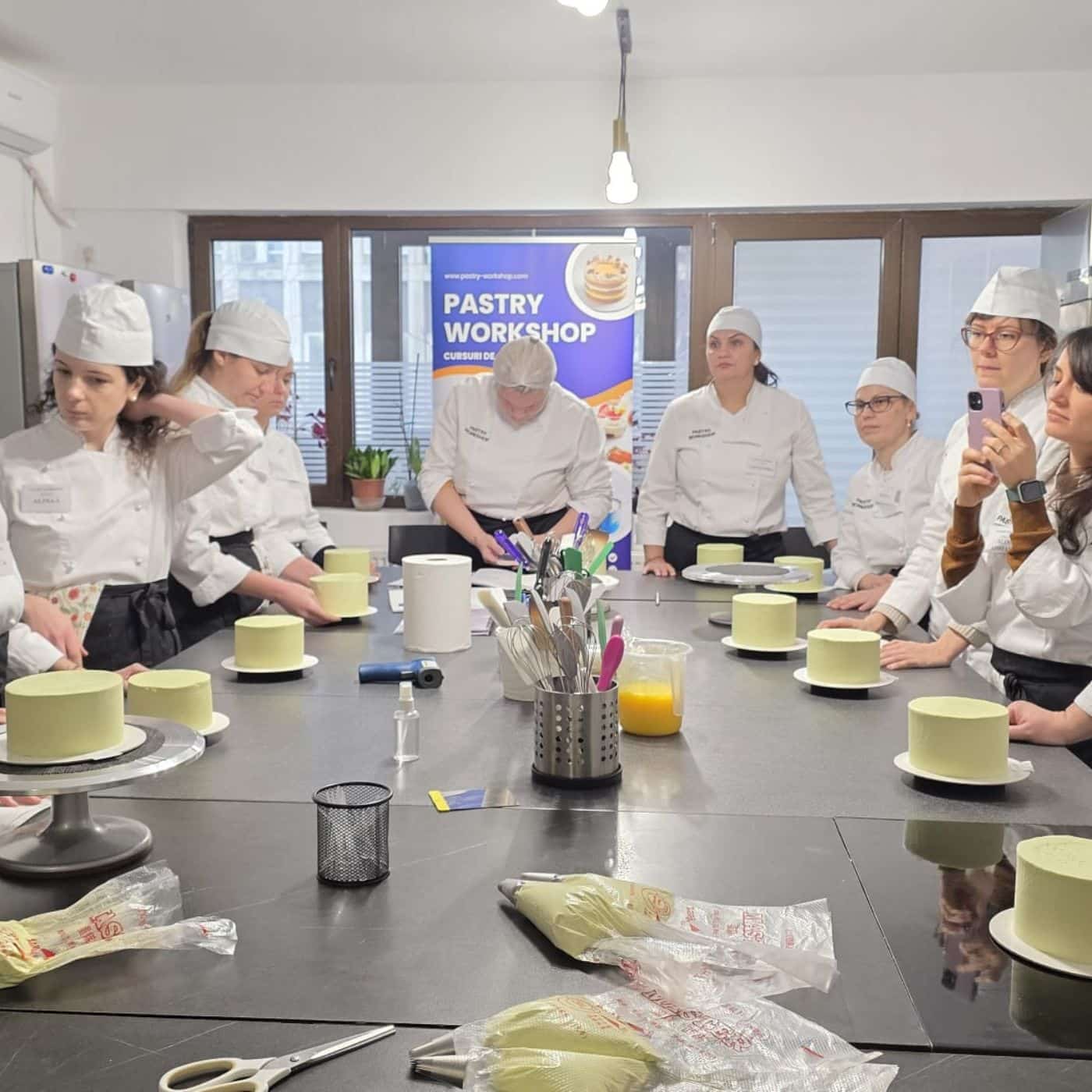 Atelier de patiserie cu participanți și prăjituri.