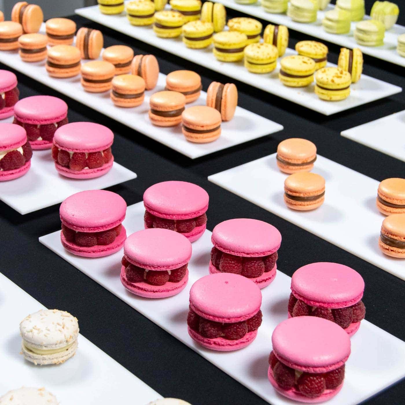 Macarons colorate aranjate pe platouri albe