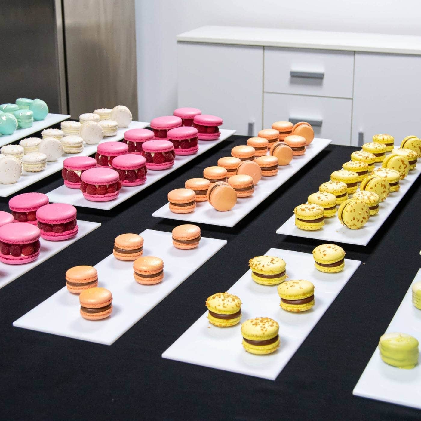 Macarons colorate aranjate pe platouri albe