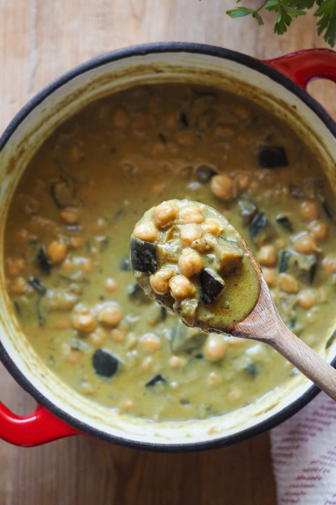 Paula's Apron Curry de Garbanzos y Berenjena en 30 minutos Esta receta de Curry de Garbanzos y Berenjena en 30 minutos es perfecta para una comida entre semana o incluso cena. Es rápida de hacer, sencilla, pero tiene una de sabor ¡increíble! Y si lo acompañas con un poco de arroz basmati y pan ya ni te digo, no dejarás ni una gota de salsita en el plato. Por cierto, si sigues alguna dieta especial, esta receta es vegana, sin gluten y sin lactosa. Aquí se ve el curry en una cazuela al fondo y una cuchara de madera con un poco del curry de garbanzos y berenjena para que se aprecien todos los detalles.