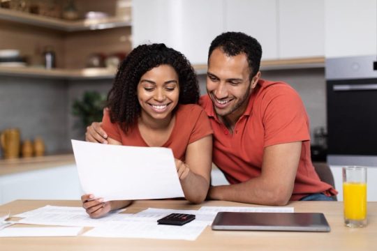 smiling-millennial-african-american-wife-husband-same-tshirts-work-with-documents-calculate-profit-min