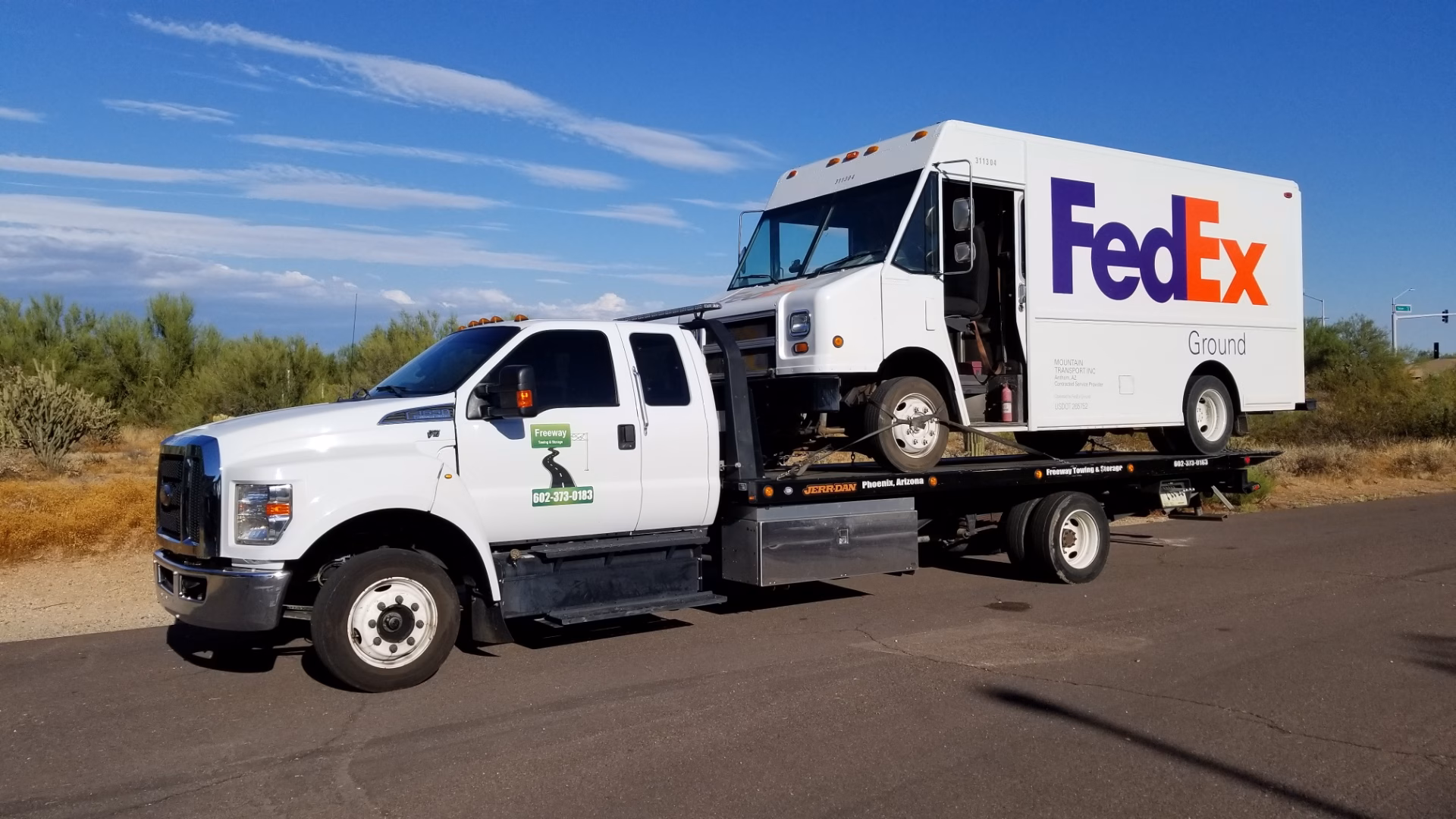 Freeway Towing & Storage flatbed tow truck transporting a FedEx Ground delivery van in Phoenix AZ