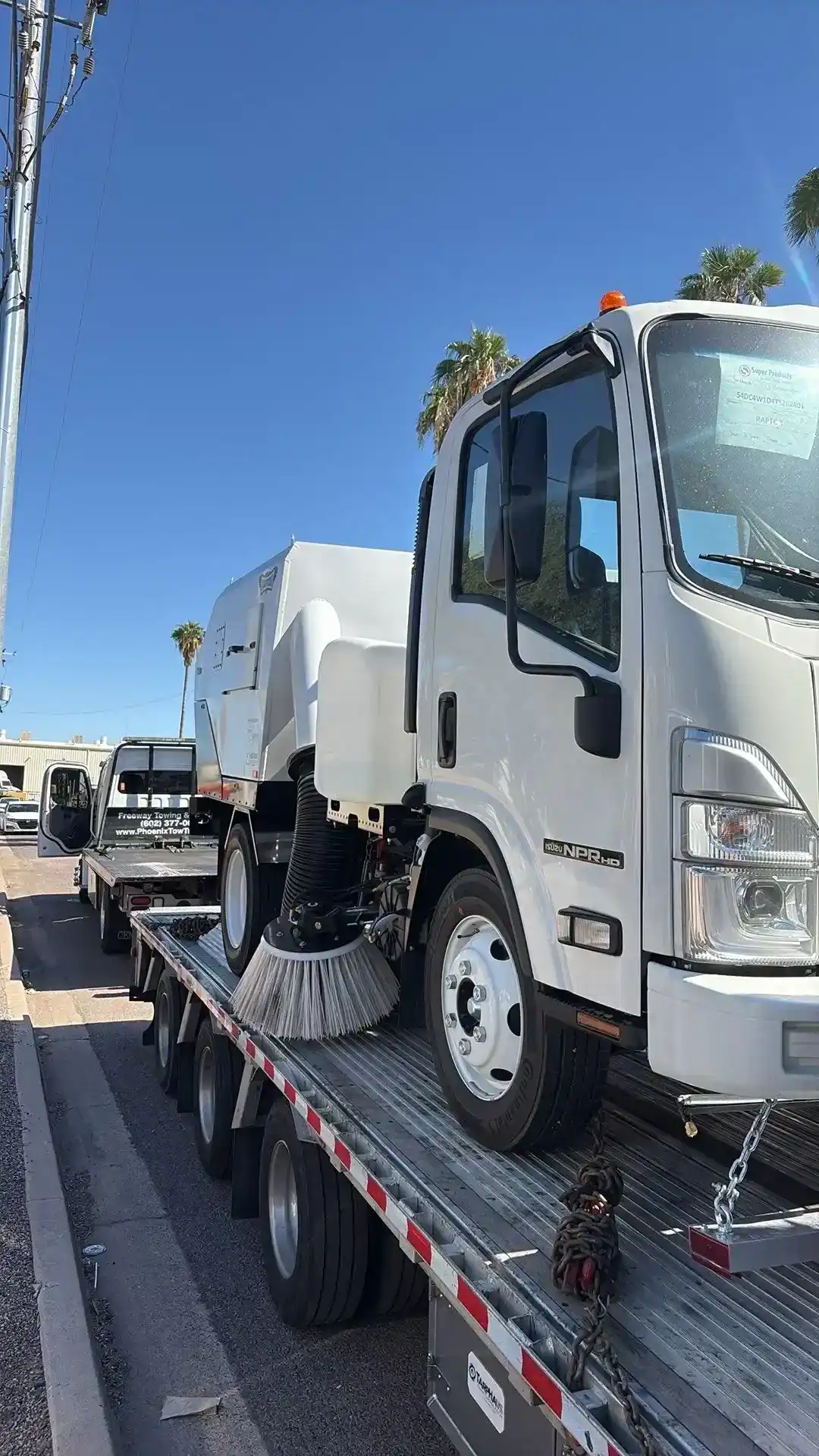 Freeway Towing & Storage undecking a street sweeper from a step-deck trailer in Phoenix, AZ