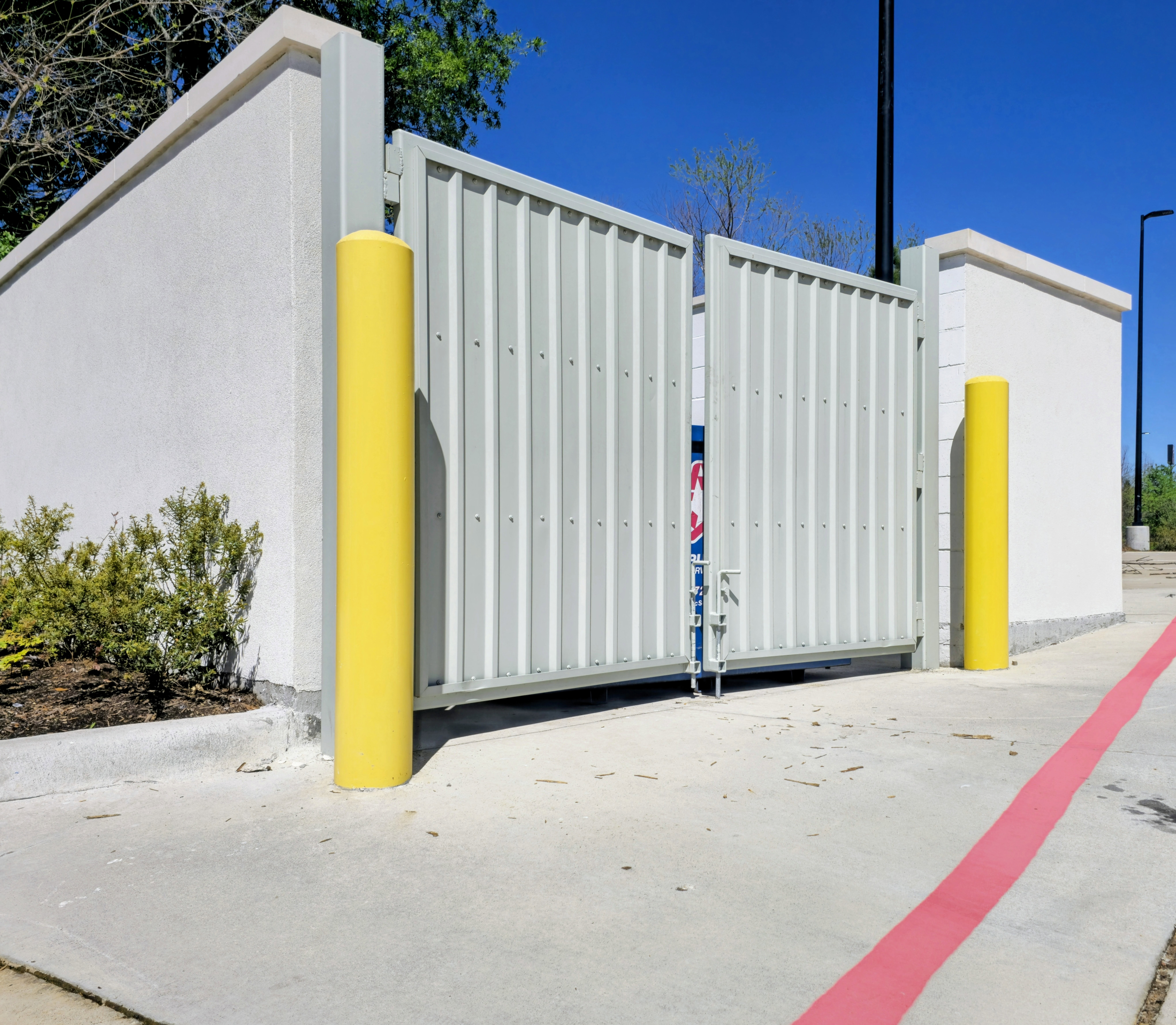 Yellow bollards painted at commercial property entrance North Houston TX | Podium Pavement Works