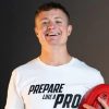 Jack McLean, in a white 'Prepare Like a Pro' t-shirt, holding a red Australian rules football, exudes joy and confidence.