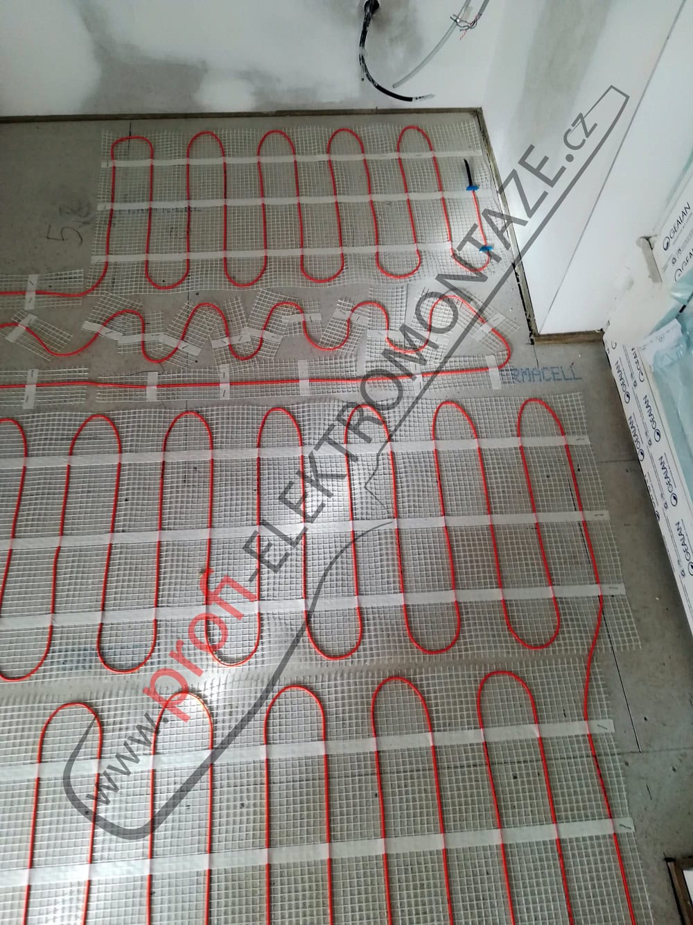 Detailní pohled na přesné tvarování a pokládku elektrické topné rohože v rohu místnosti