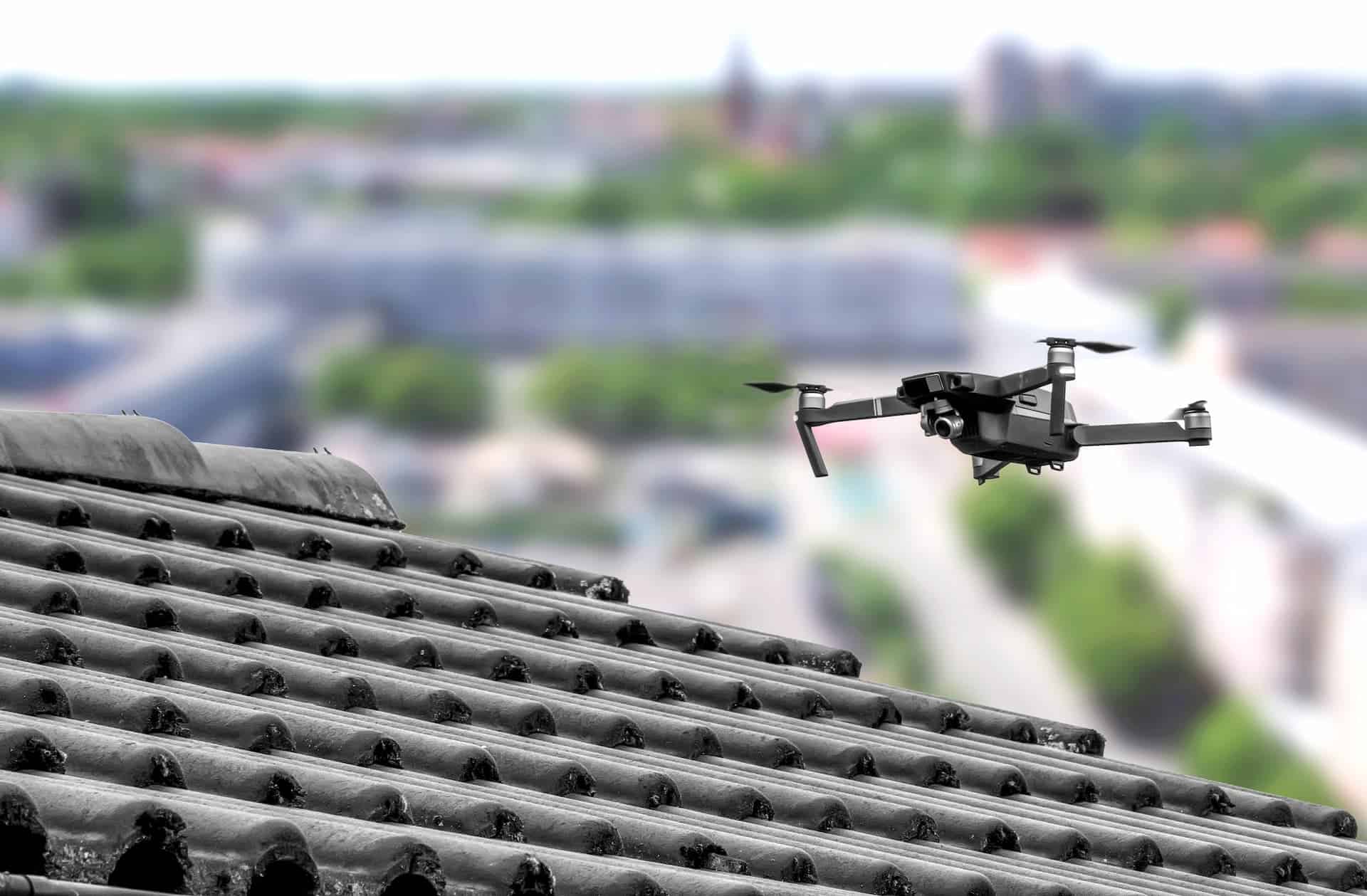 black drone performing a roof inspection on a tile roof