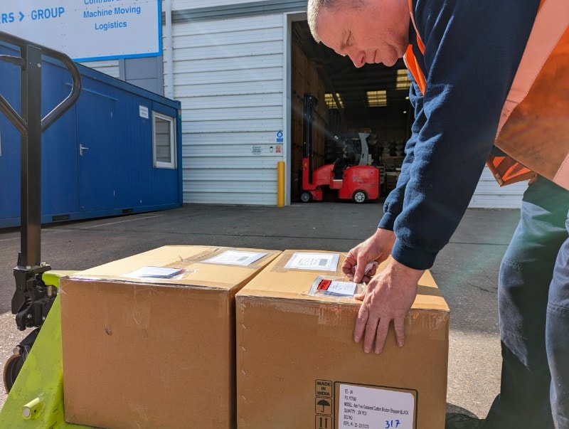 storage of goods with man attaching label to cardboard box